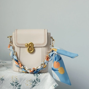 Détail du mini sac seau crème avec fermoir doré et bandoulière en foulard à fleurs