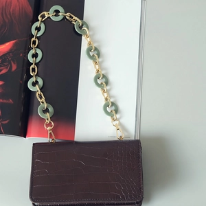 Detail of dark brown faux crocodile bag with mixed gold metal and resin chain strap