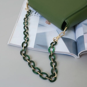 Détail de la chaîne en résine acrylique verte avec maillons dorés sur sac en cuir