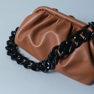 Detail of caramel pleated cloud pouch with chunky glossy black resin chain strap