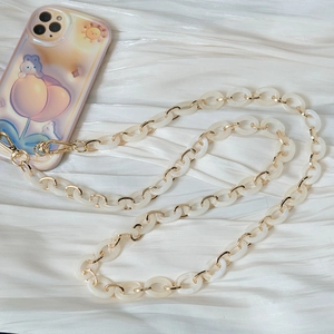 Détail de la chaîne de téléphone en résine blanche et métal doré sur tissu en soie douce