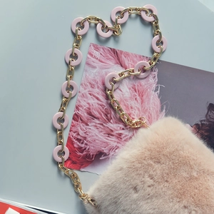 Detail of faux fur bag with golden metal chain and pink resin ring strap on magazine