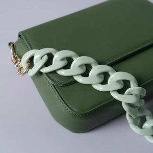 Close-up of deep green bag with mint green acrylic chain strap and gold hardware