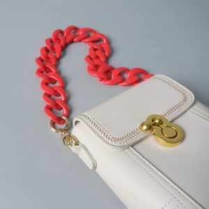 Detail of cream leather mini bag with bold red acrylic chain strap and gold clasp