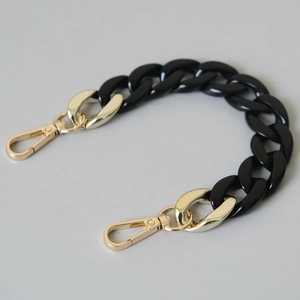 Detail of chunky black acrylic fishbone chain with golden lobster clasps for phone or bag