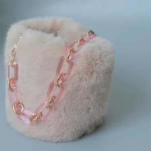 Dettaglio della catena in acrilico rosa e metallo dorato su ecopelliccia beige