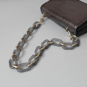 Detail of dark brown crocodile embossed purse with matte grey and gold thick chain strap