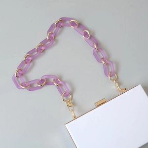 Detail of white evening bag with chunky purple frosted chain and gold metal hardware accents