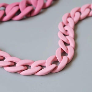 Close-up of pink acrylic curb chain with matte resin texture for handbag decoration