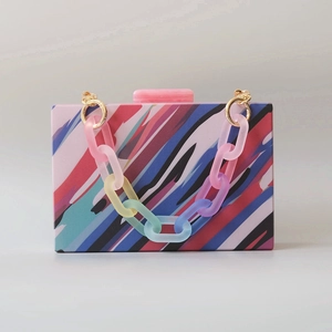 Detail of colorful striped acrylic evening clutch bag with rainbow chain handle