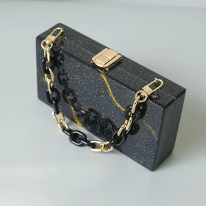 Dettaglio della pochette da sera con paillettes nere, venature dorate e tracolla a catena
