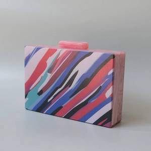 Detail of multi-colored acrylic evening clutch bag showing marble textured side and clasp