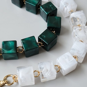 Detail of vintage acrylic cube chain with green marble texture and gold metal rings
