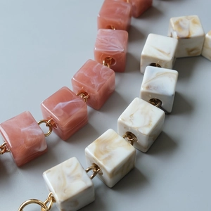Close-up of pink and cream marble resin cube bead chain with golden metal rings