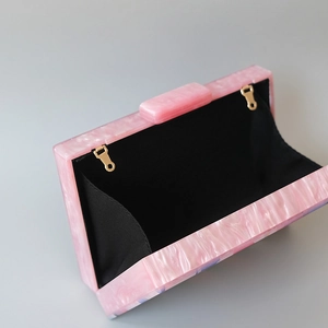 Detail view of pink marble acrylic clutch bag showing interior lining and golden metal hooks