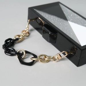 Nahaufnahme der geometrischen Acryl-Box-Clutch mit silbernem Glitzer und Harzkette