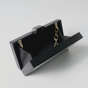 Detailansicht der schwarzen Acryl-Abendtasche mit goldener Kette und schwarzem Stofffutter