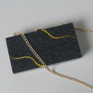 Dettaglio della pochette da sera con glitter neri, paillettes dorate e catena in metallo