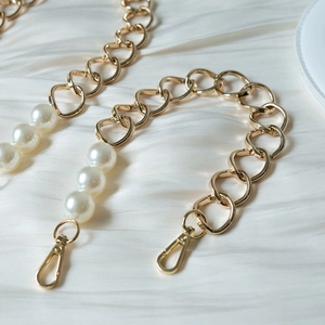 Detail of luxury gold metal chain with large white pearls and lobster clasps for handbags