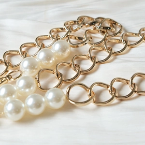 Golden metal handbag chain strap featuring large white pearls and secure lobster clasps