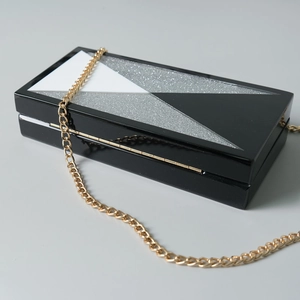Detail der Acryl-Abendtasche mit schwarz-weißen geometrischen Dreiecken und Goldkette