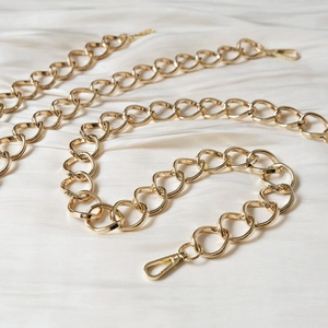 Detail of a golden heart-shaped metal link chain with polished lobster clasps for handbags