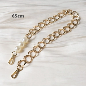 Close-up of a 65cm gold metal bag chain with faux pearls and lobster clasps on silk
