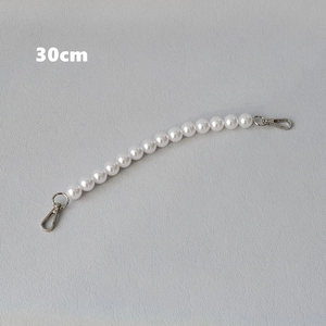 Detail view of a 30cm white pearl bag strap with silver metal lobster clasps