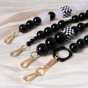 Close-up of black and white resin beaded chain with checkered cubes and gold metal clasps