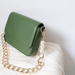 Detail of dark green PU leather bag with chunky gold chain and large white pearls