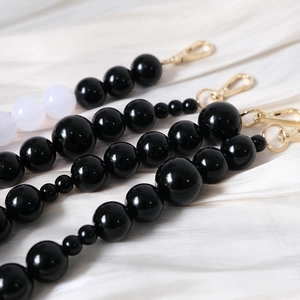 Close-up of black and white acrylic beaded chain strap with golden metal lobster clasps