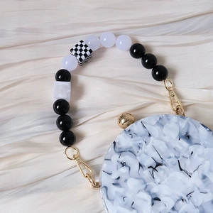 Detailed close-up of marble pattern round clutch with vintage acrylic beaded handle