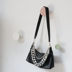 Close-up of black crossbody bag with silver Cuban chain links and lychee texture