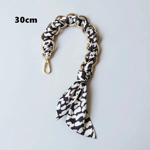 Detail der 30 cm goldenen Handtaschenkette mit schwarz-weiß gepunktetem Seidenschal