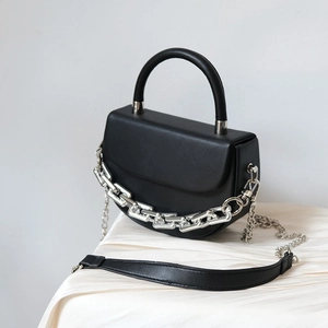 Detail of black leather crescent bag with bold silver metal chain and round handle