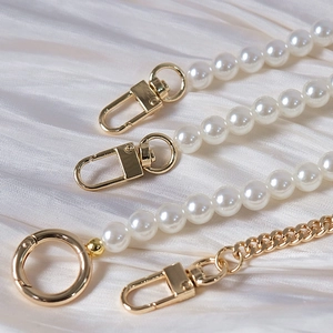 Detail of luxury pearl beads and golden metal chain straps with lobster clasps