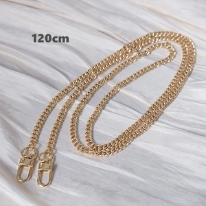 Macro shot of 120cm golden Cuban link bag strap with lobster clasps on white satin