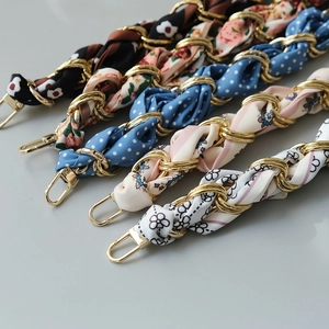 Detail of silk scarf intertwined with golden metal chain links for handbags