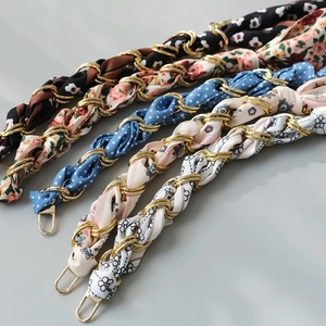 Detail of silk scarf intertwined with gold metal chain for handbag handles