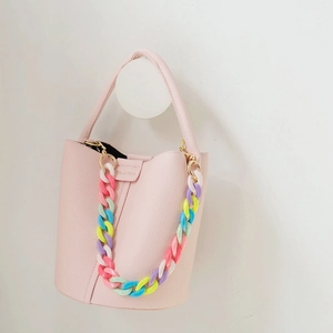 Light pink pebbled leather bucket bag featuring a vibrant candy-colored acrylic chain strap