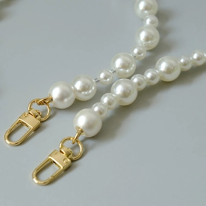 Détail des perles blanches de tailles variées avec fermoirs mousquetons dorés élégants