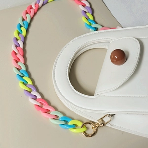 Detail of white leather bag featuring a multi-color resin chain strap and golden buckle