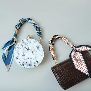 Detail of silk scarf handles on marble acrylic and brown crocodile leather handbags