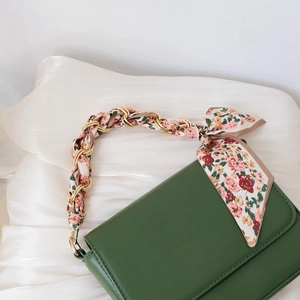 Dark green handbag with golden chain handle wrapped in floral silk scarf for women