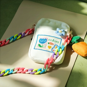 Detail of white canvas crossbody bag with colorful acrylic chain and tulip embroidery