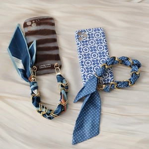 Detail of elegant silk scarf and gold chain handle straps on two floral phone cases