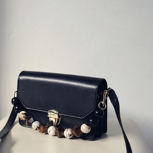Detail of vintage black flap bag featuring decorative large amber and black marble beads