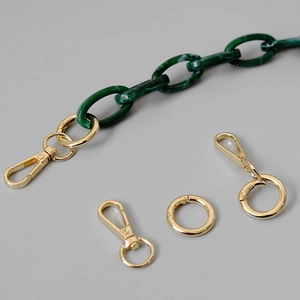Detail view of marble-textured green resin chain links with shiny gold metal lobster clasps