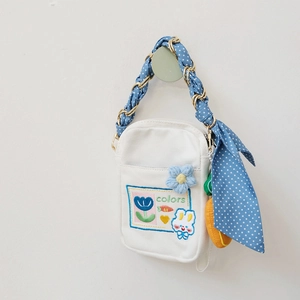 Detailed embroidery and blue polka dot silk ribbon handle on a white canvas mini bag