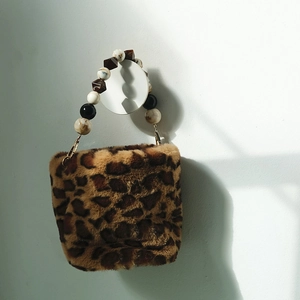 Detail of leopard print faux fur handbag featuring acrylic beaded handle and gold metal clips